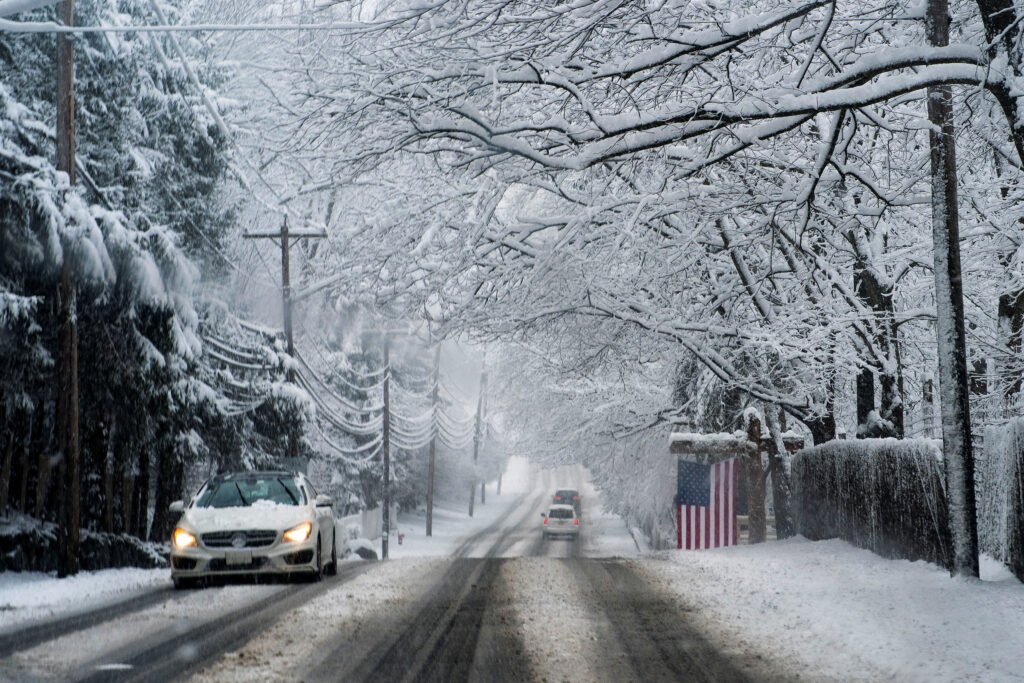 Cars drive under the snow along the Closter Dock Road in Alpine, New Jersey